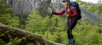 hiker with poles and wearing backpack in forest